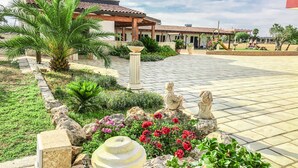 A courtyard with a tiled floor, palm trees, and statues. - Il Mondo dei Sogni (Nardò)
