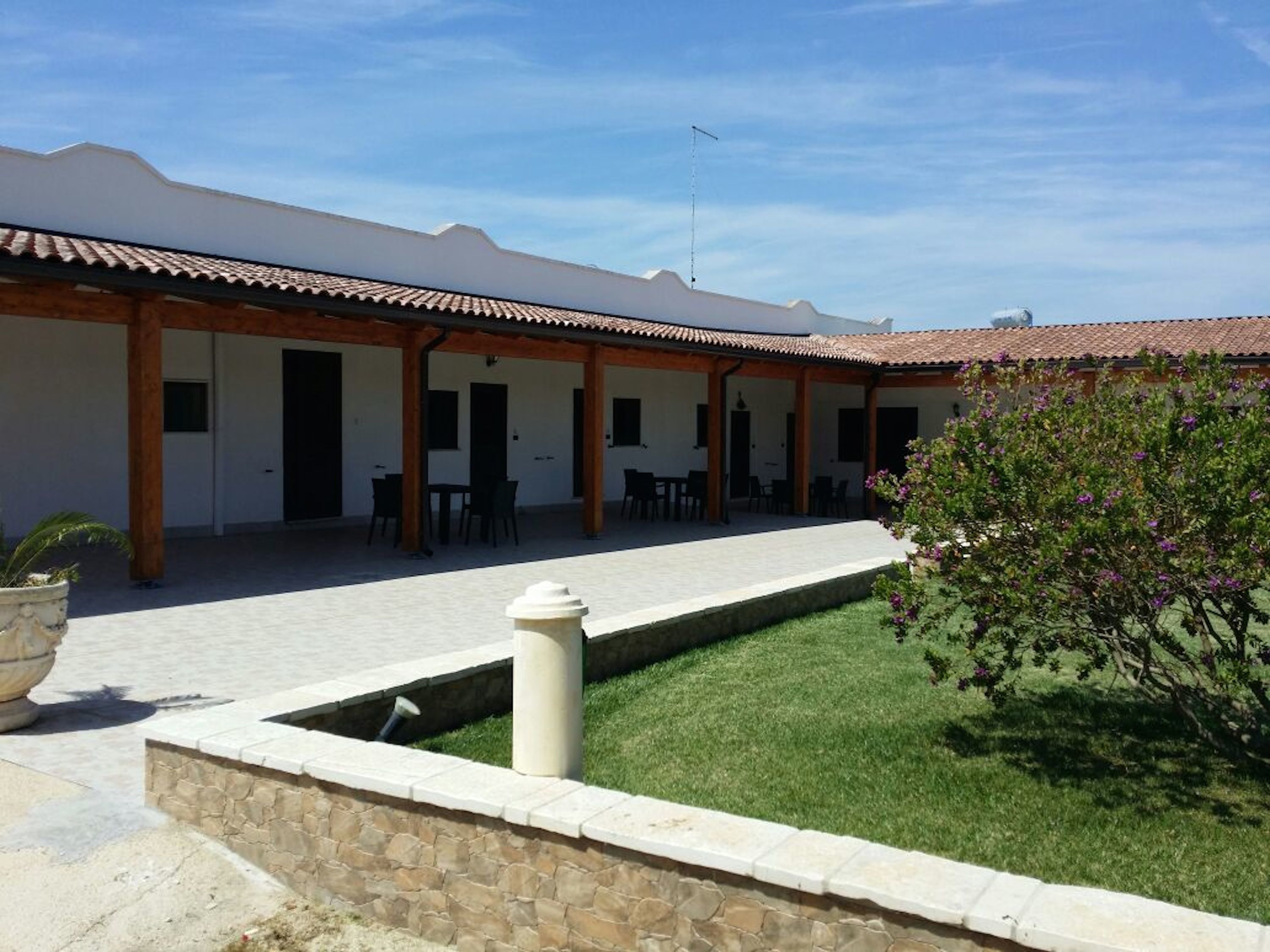 A courtyard with a covered seating area, stone walls, and a small water feature.