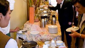 A buffet setup with various dishes and a waiter serving guests.
