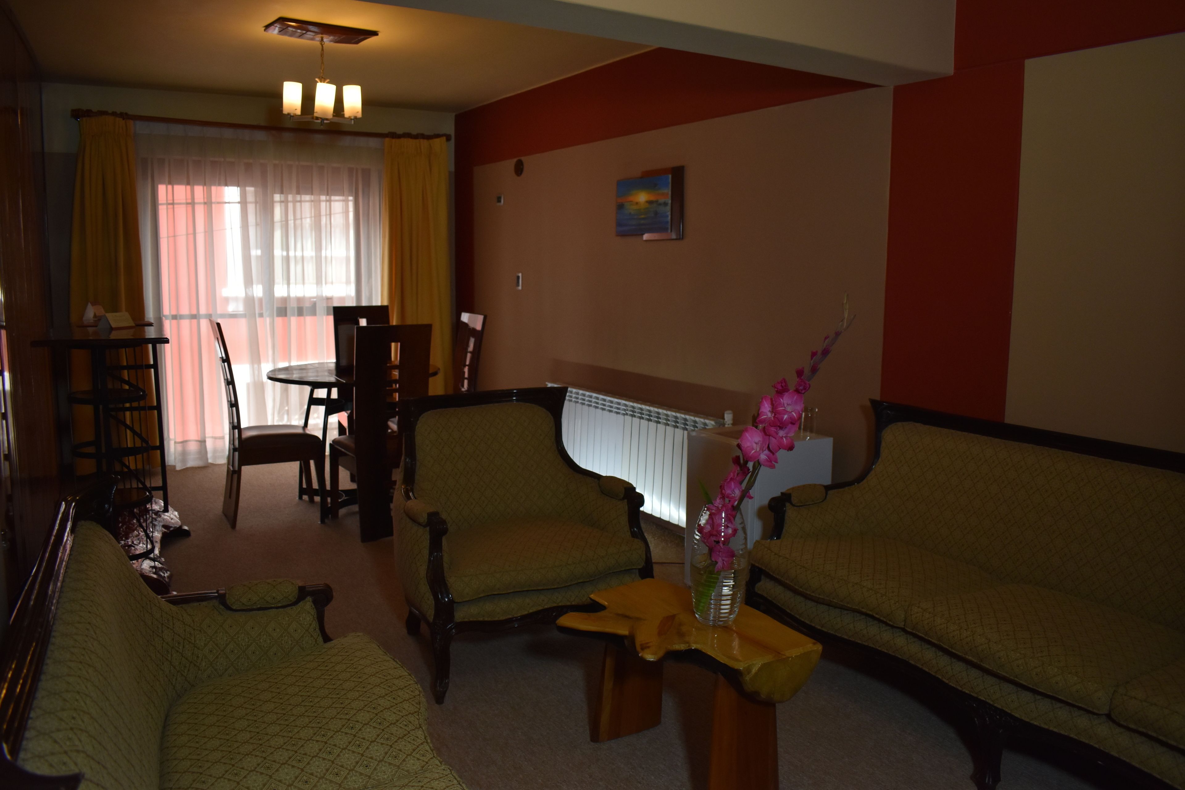 A living room with a sofa, armchairs, a coffee table, and a dining area with a table and chairs.