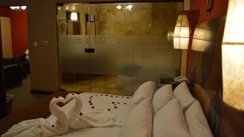 Una habitación de hotel con cama, baño y puerta de vidrio que da a una zona de ducha.