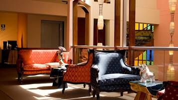 Un hall d’hôtel avec un canapé, des fauteuils et une petite table agrémentée d’un objet décoratif.