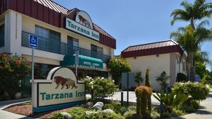 En byggnad som tillhör Tarzana Inn, med en lejonlogotyp, en skylt vid hotellentrén och en skylt som visar att anläggningen är tillgänglig för personer med funktionsnedsättning.