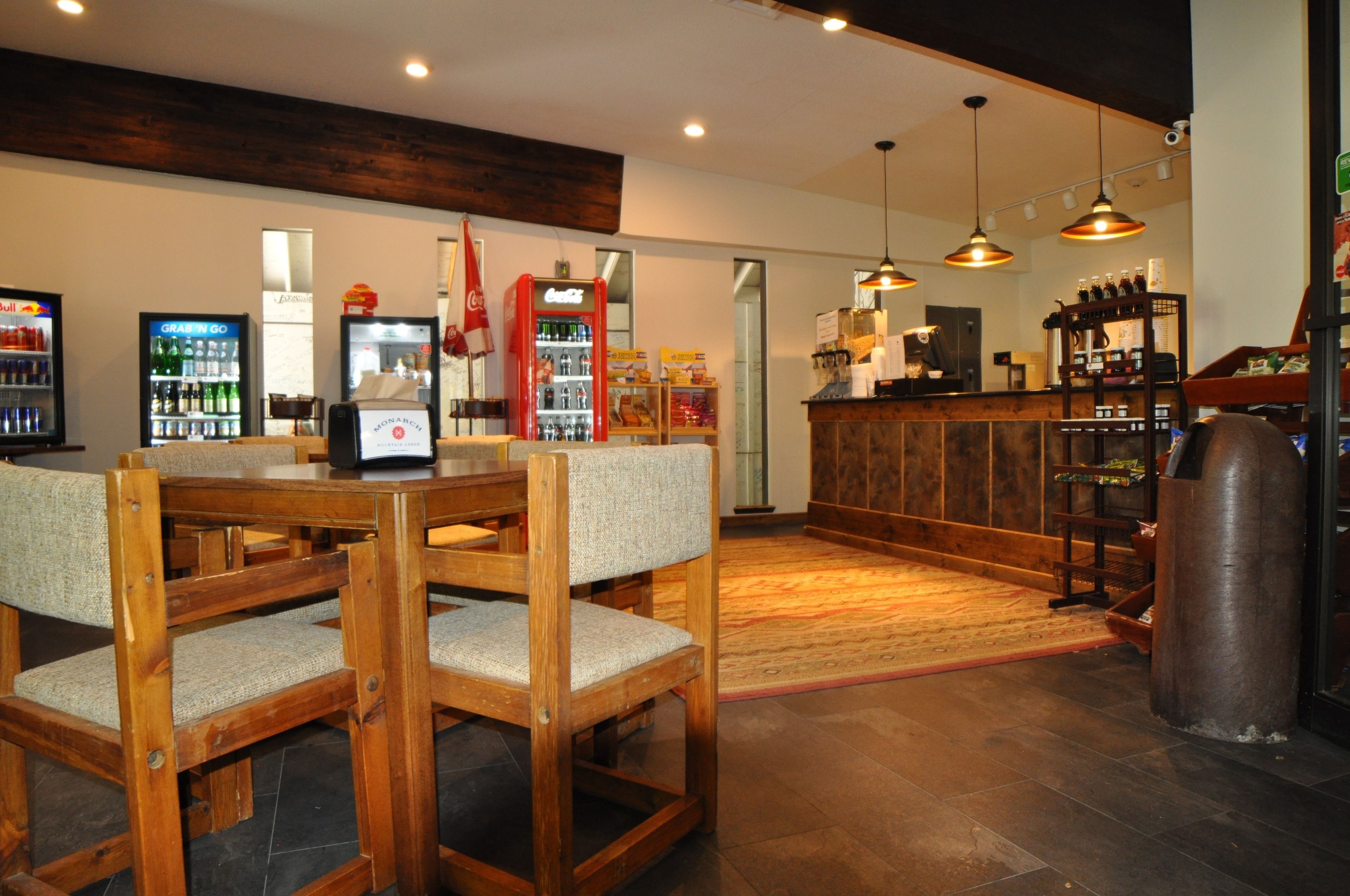 Un restaurant avec des meubles en bois, un coin bar et un réfrigérateur rempli de Coca-Cola.