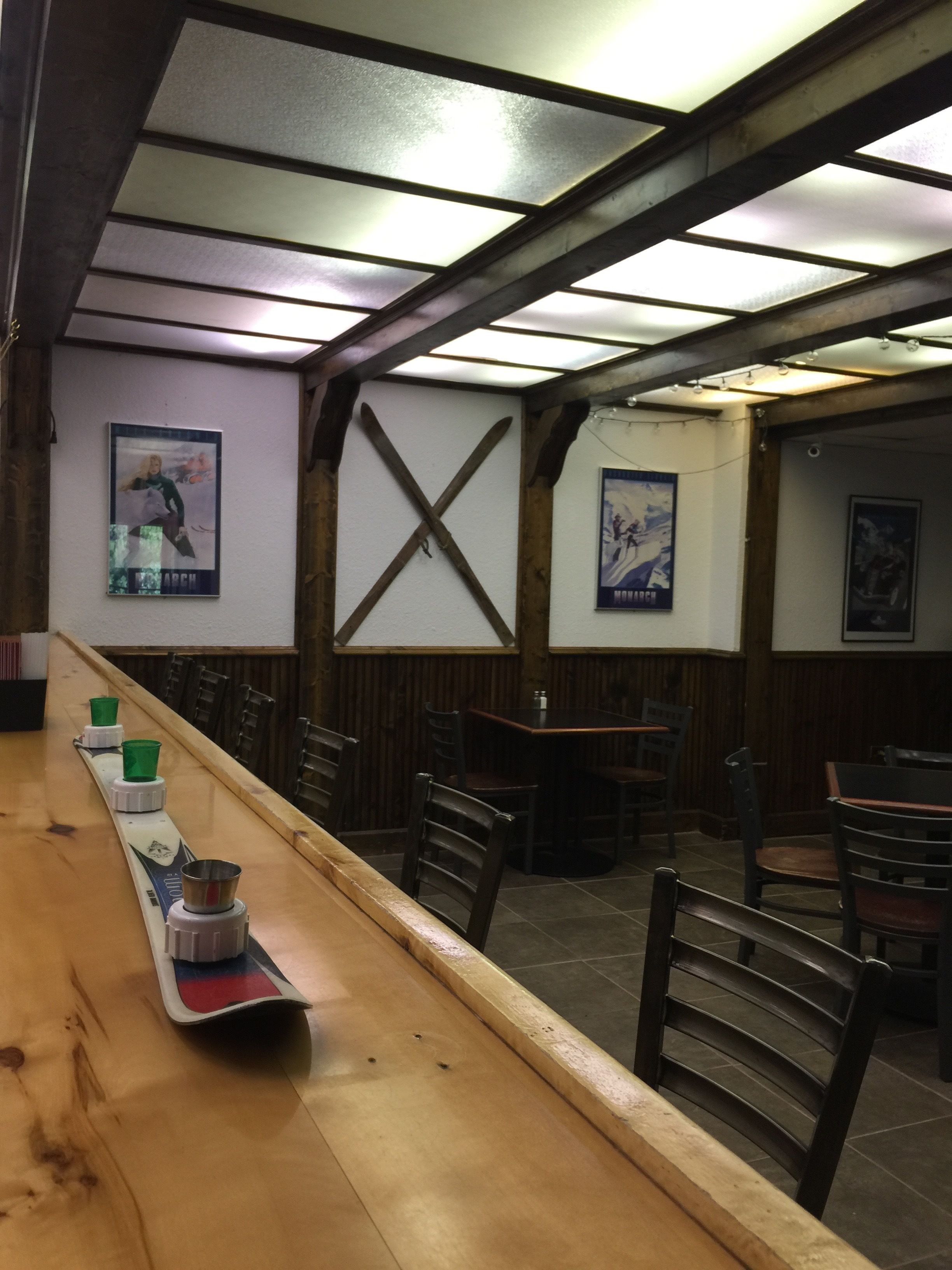 A restaurant interior with wooden beams, a long wooden table, and several chairs.