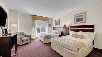 A hotel room with a large bed, a smaller bed, a desk, a chair, and a television.