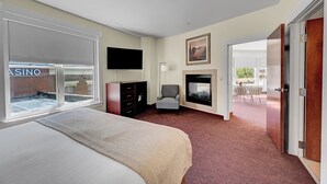 Hotelkamer met een groot bed, een flatscreen televisie, een open haard en uitzicht op een casino door het raam.