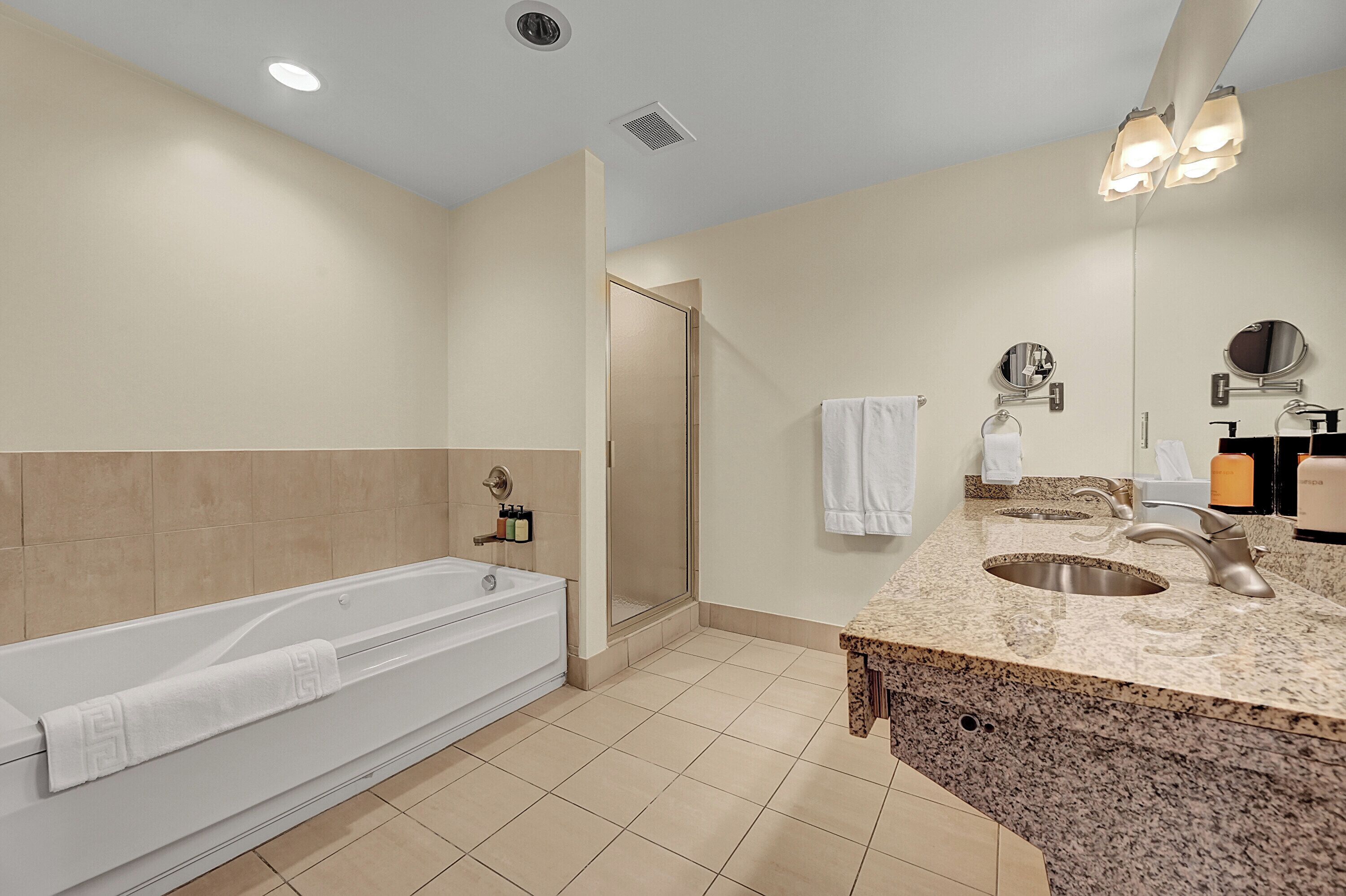A modern bathroom with a bathtub, shower, sink, and two mirrors.