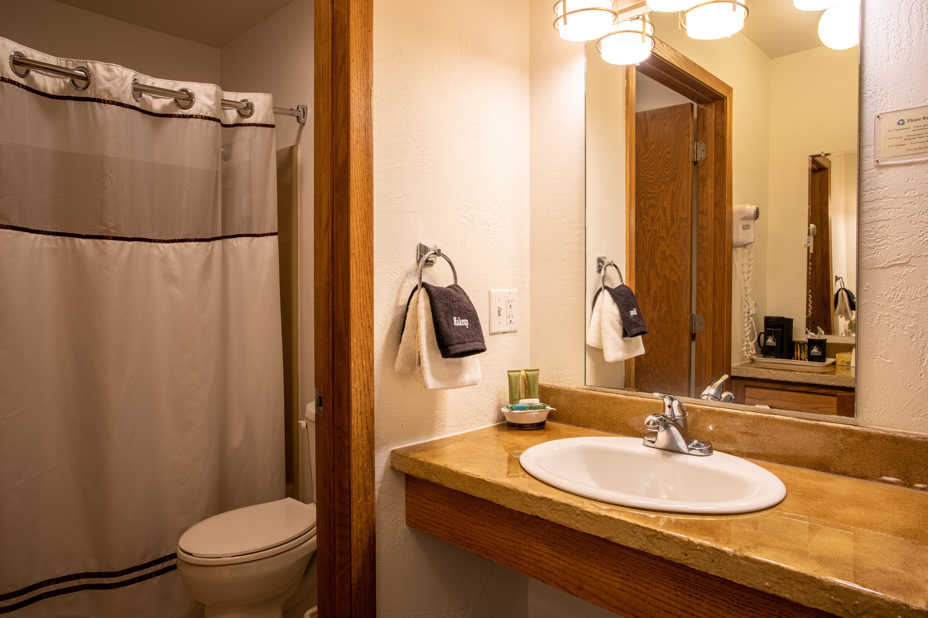 A bathroom with a shower curtain, a toilet, a sink with a mirror, and a towel rack with towels.