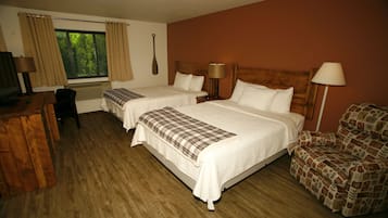 A hotel room with two beds, a desk, a chair, and a window with curtains.
