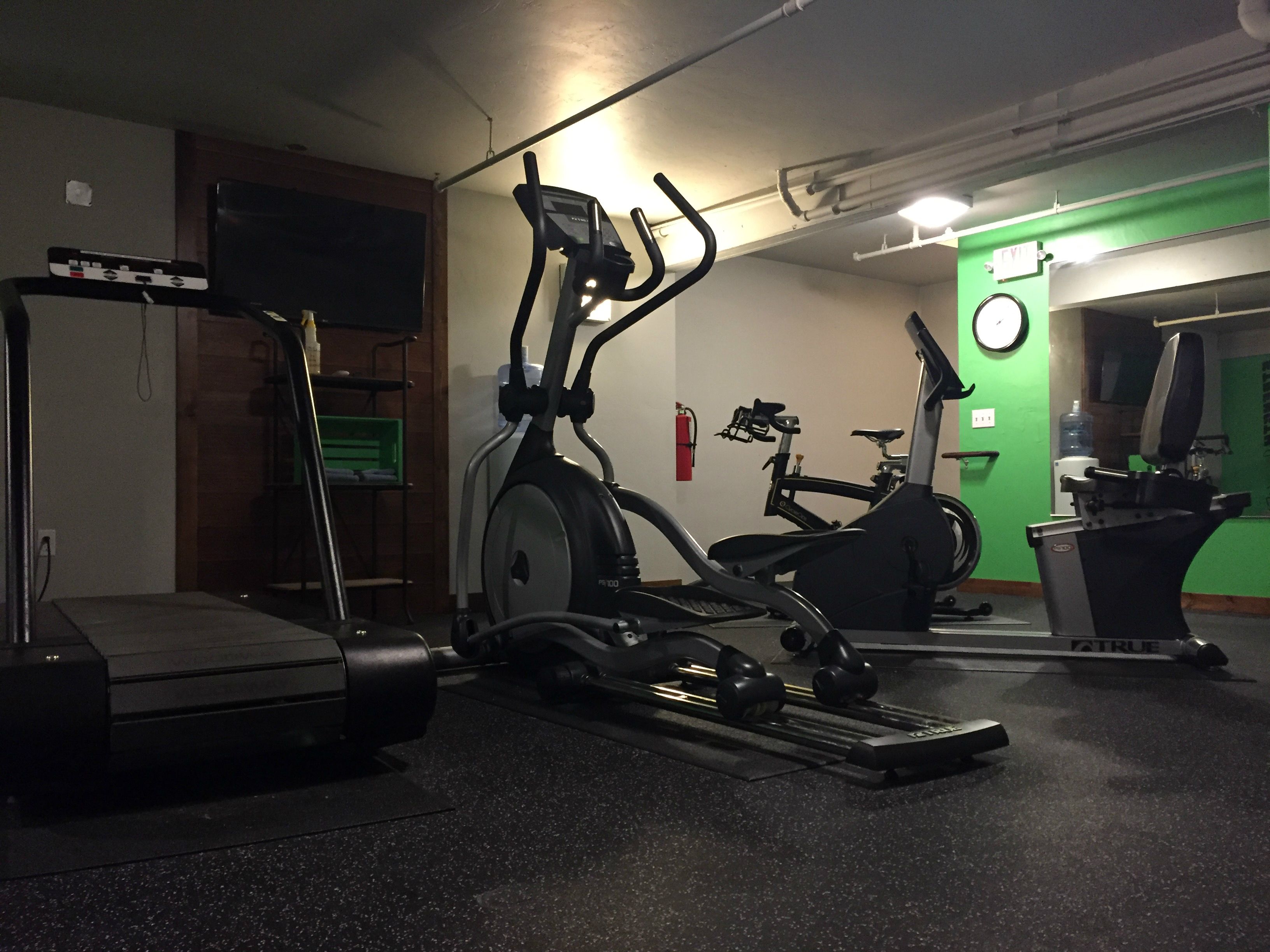 Un gimnasio con bicicletas estáticas, una elíptica y una cinta de correr.
