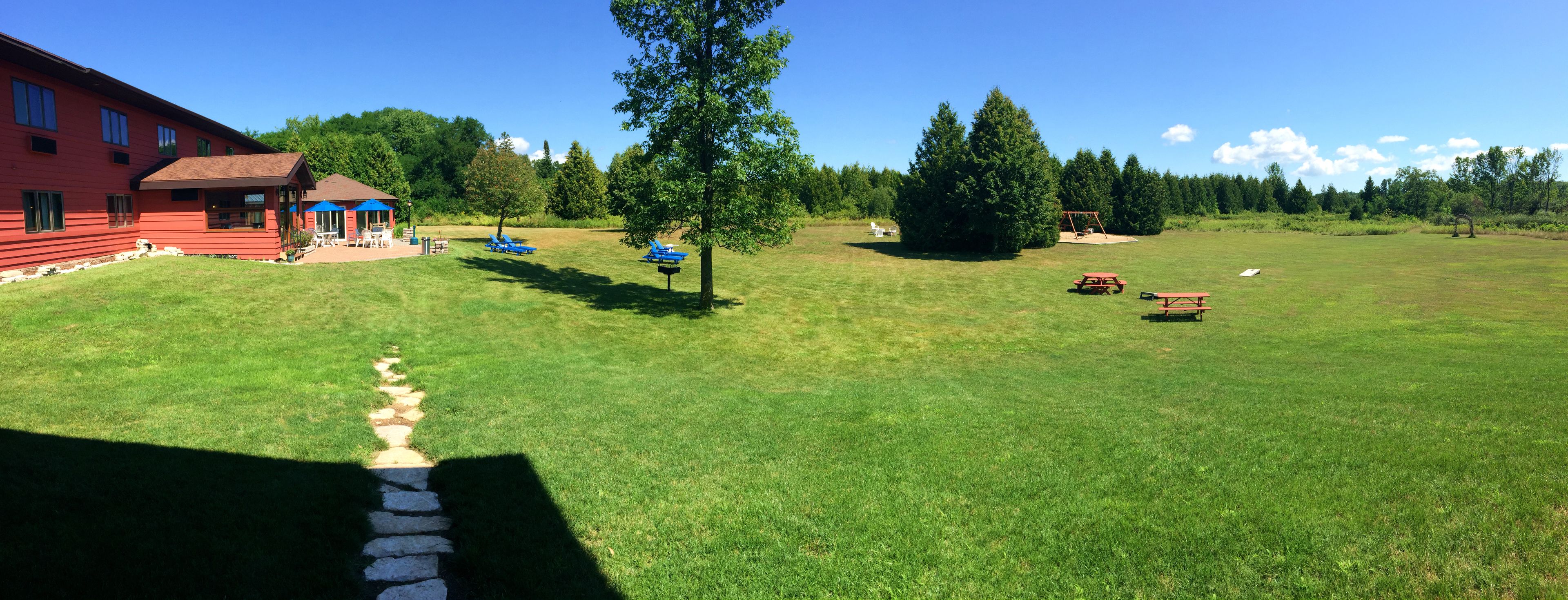 A red building with a covered patio, a picnic area, and a stone pathway.