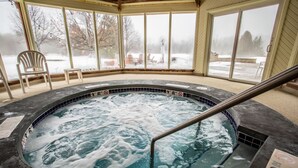 Un jacuzzi con vistas a un paisaje nevado a través de grandes ventanales.
