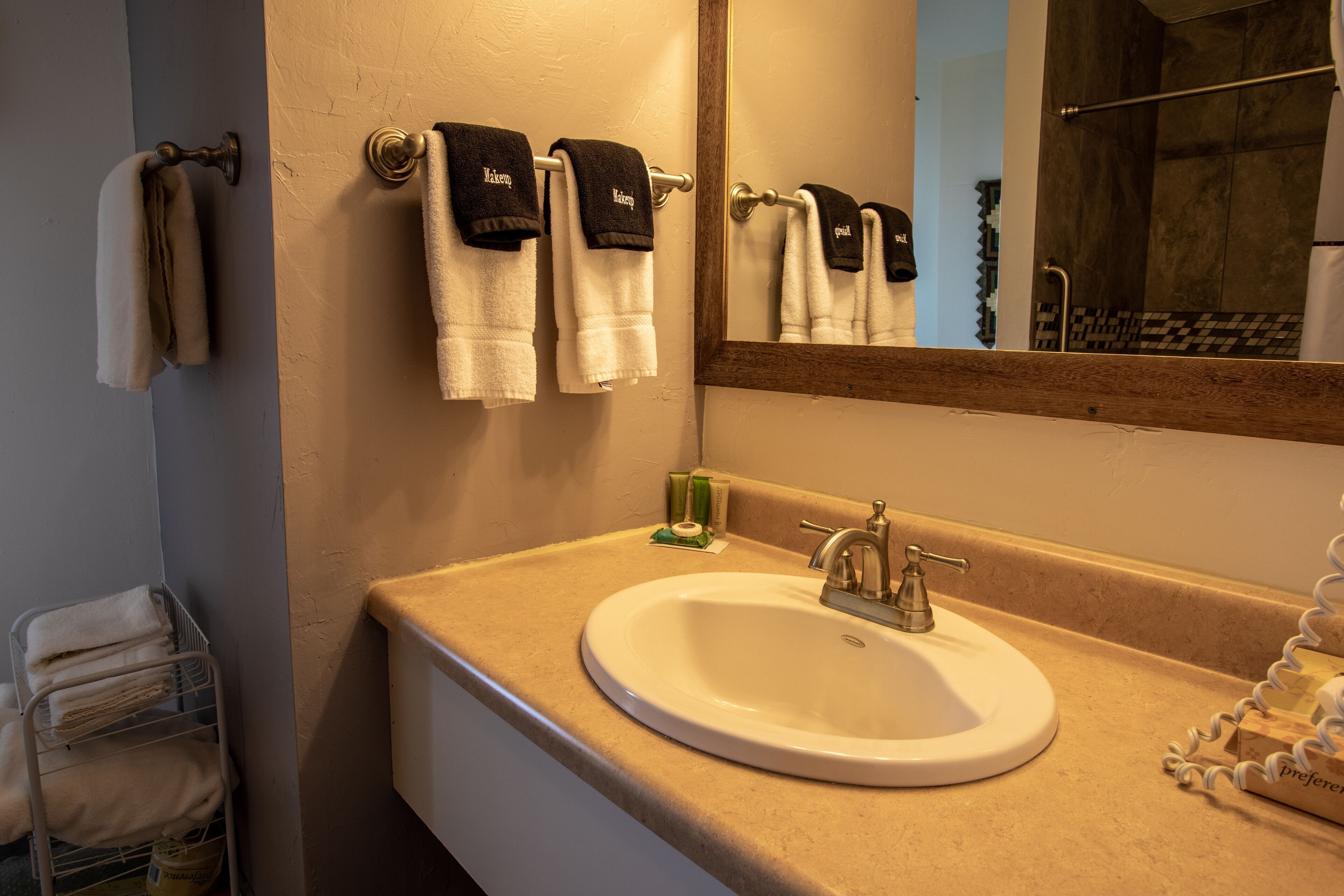 A bathroom with a beige sink, a mirror, and towels hanging on a rack.