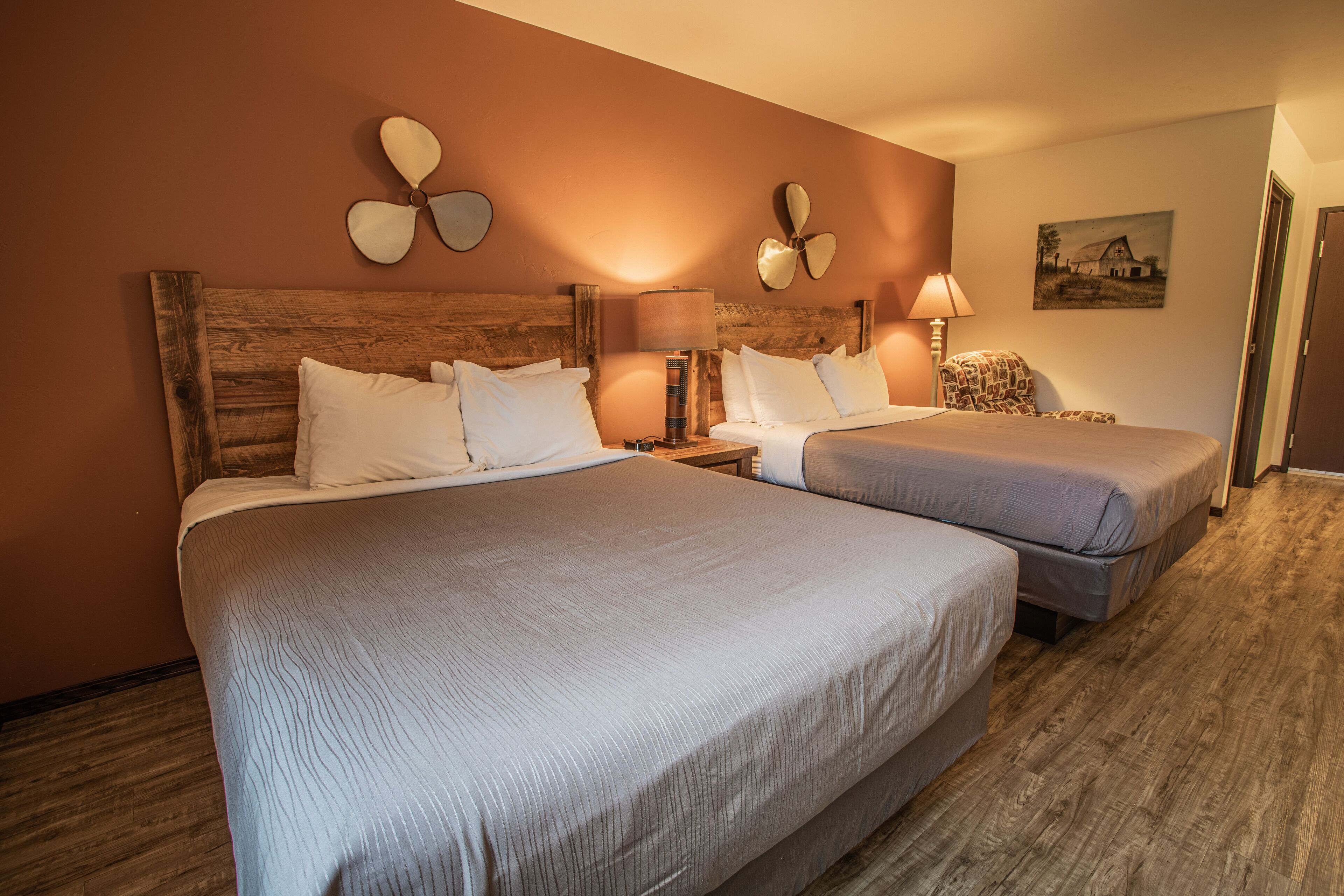 A hotel room with two beds, wooden headboards, and a wooden floor.