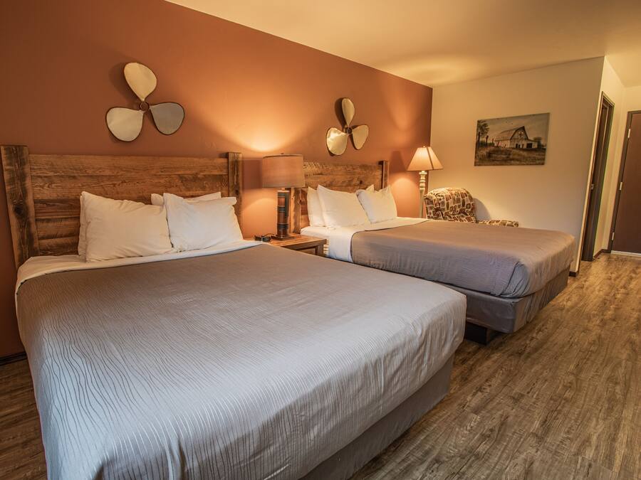 A hotel room with two beds, wooden headboards, and a wooden floor.