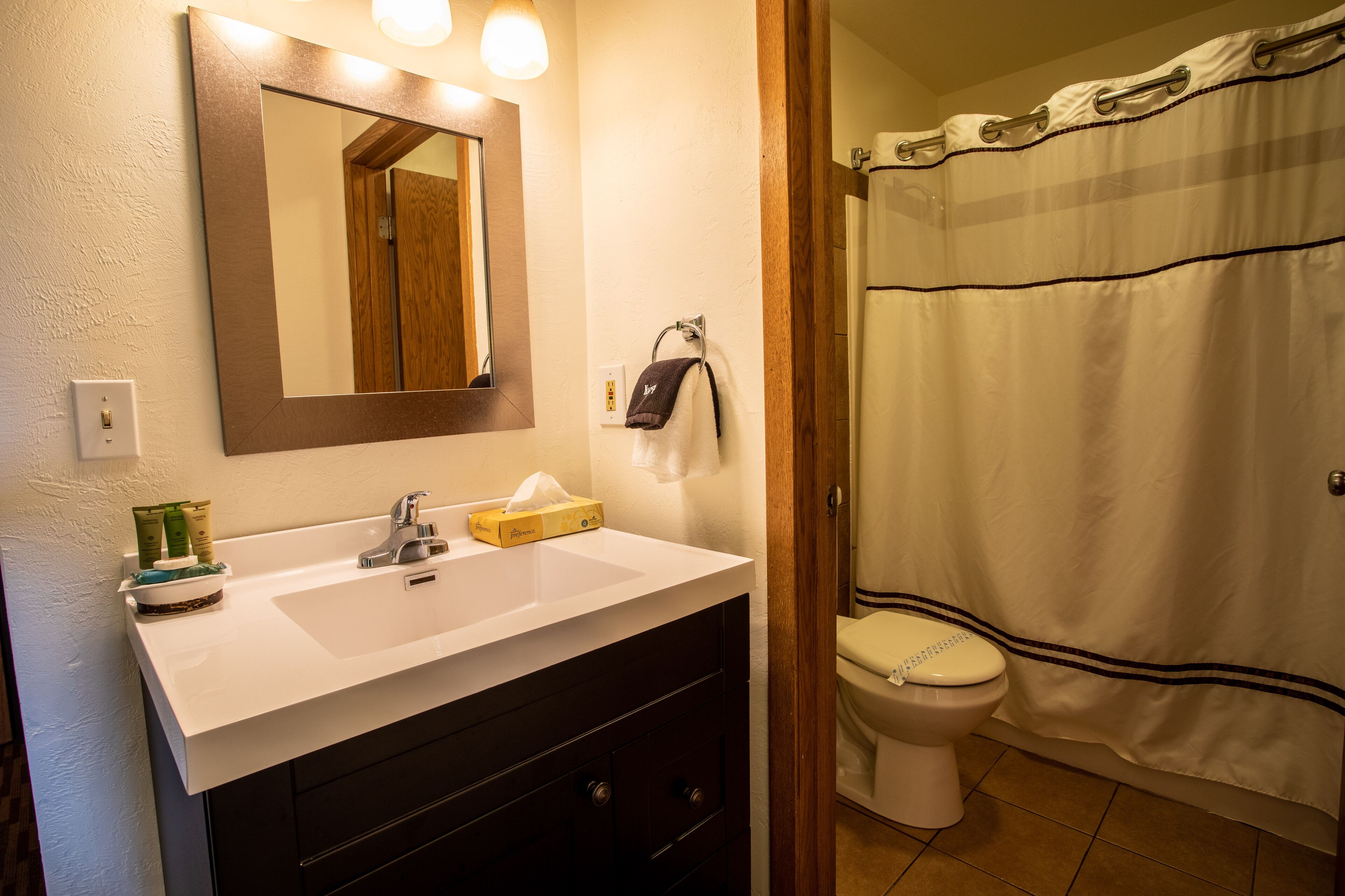 A bathroom with a white sink, a mirror, a towel rack, a toilet, and a shower curtain.