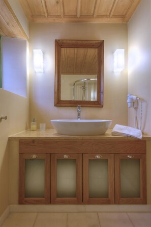 A bathroom with a wooden vanity, a large mirror, and a built-in sink. - Ritsos Guesthouse (Monemvasia)