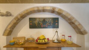 A wooden table with a bowl of fruit, a glass pitcher, and a decorative plate. - Ritsos Guesthouse (Monemvasia)