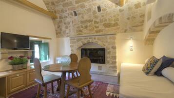 Una habitación acogedora con techo de piedra, chimenea, comedor con mesa y sillas, y sofá con cojines.