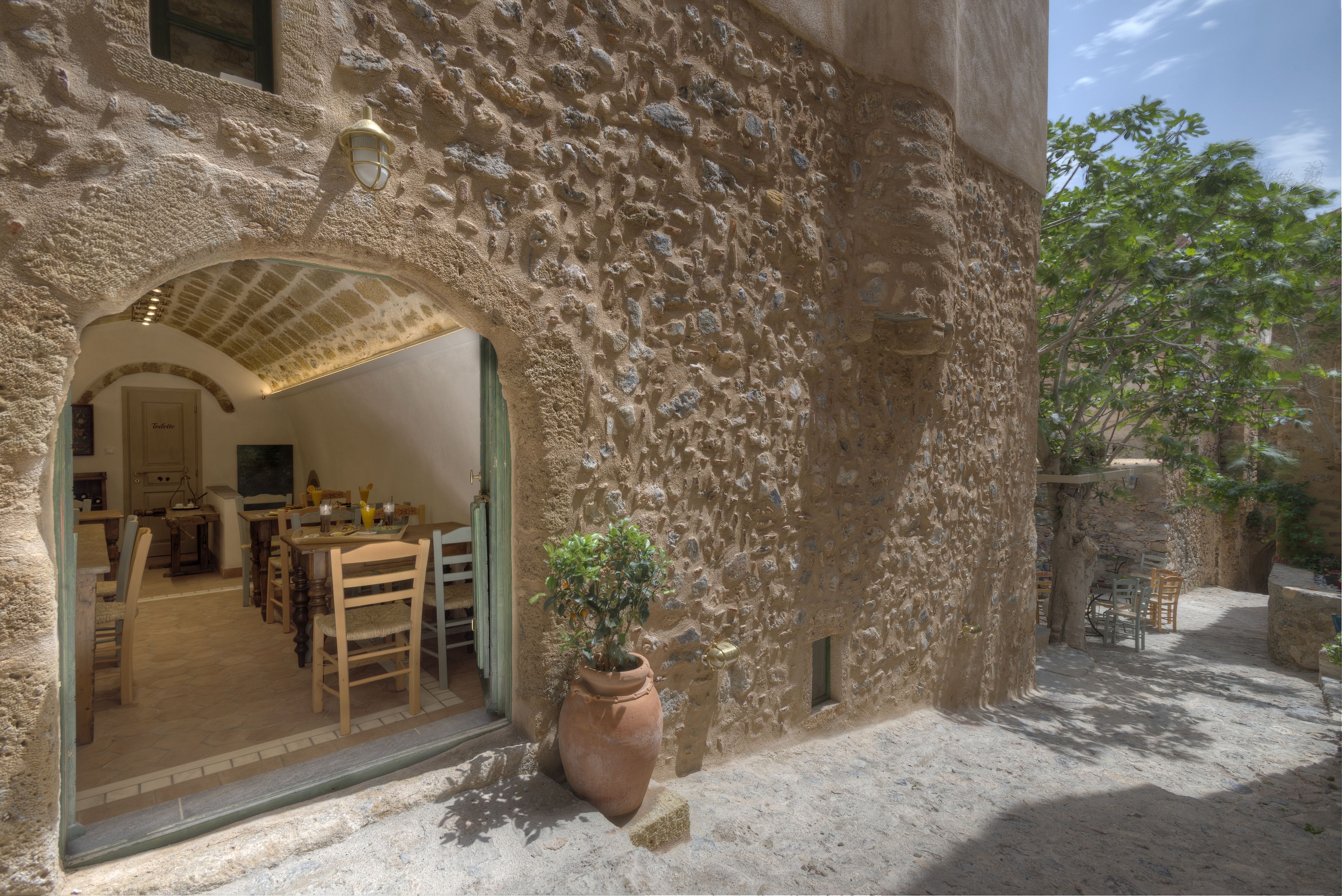 Un edificio rústico de piedra, con un área de comedor visible a través de un arco.