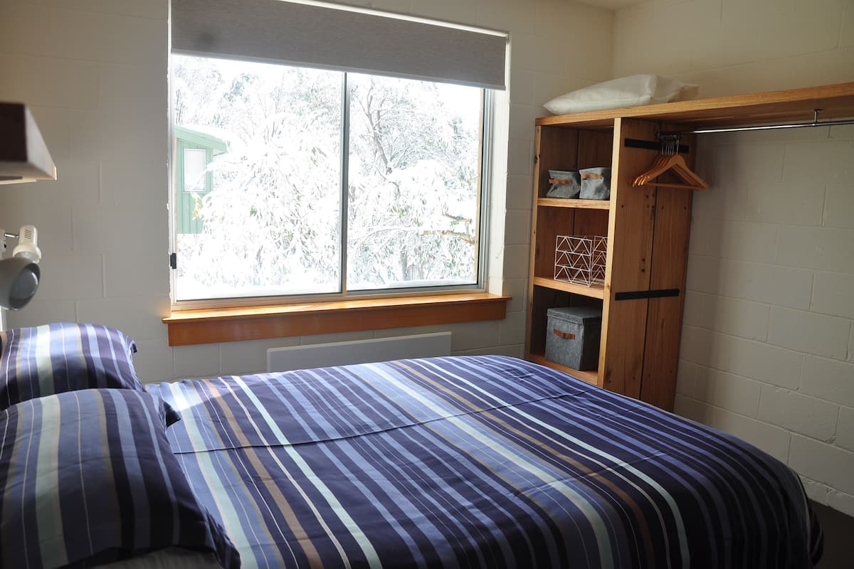 A bedroom with a bed, a window, a wardrobe, and a radiator.