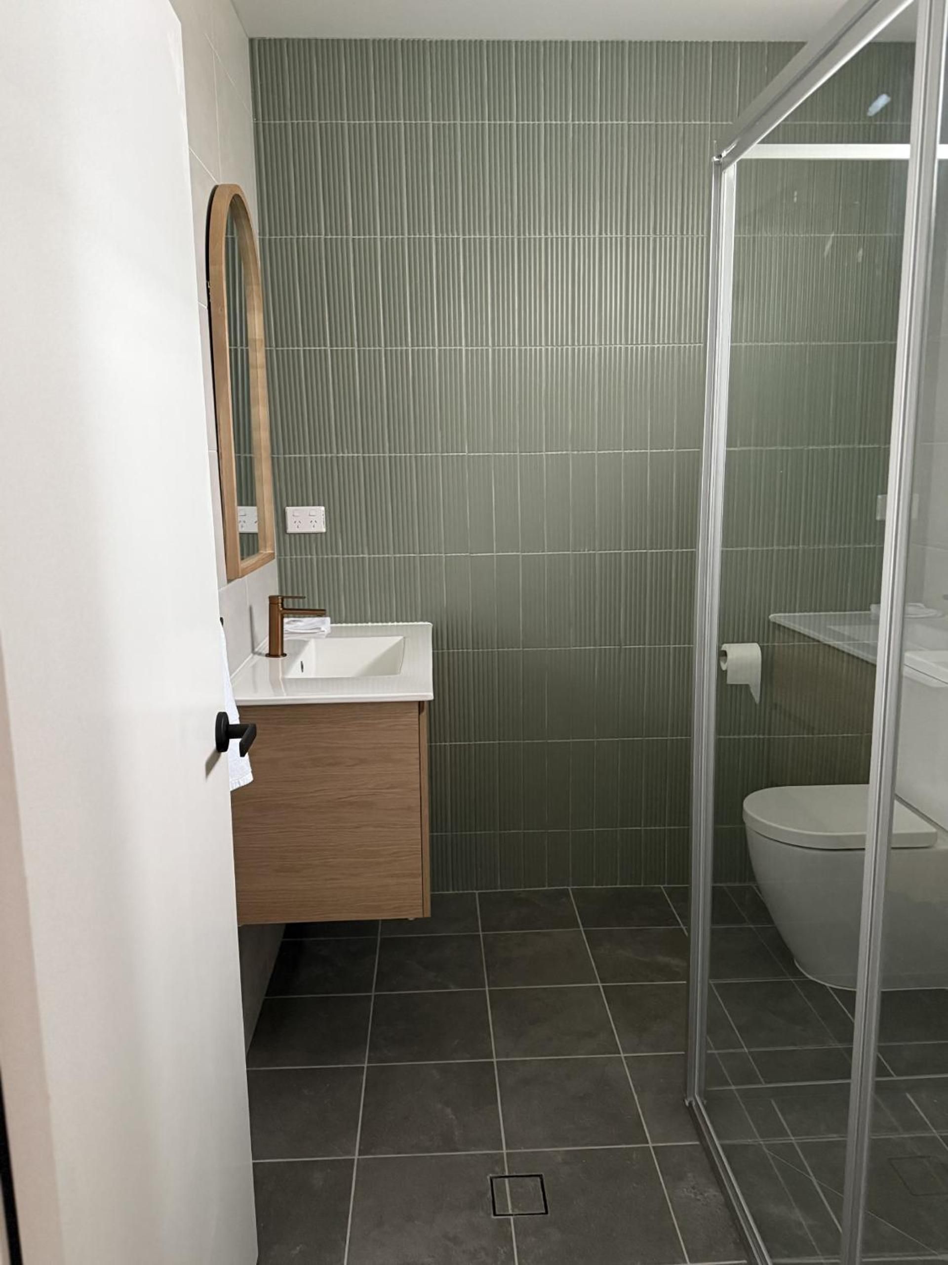 A modern bathroom with a shower enclosure, a toilet, and a vanity with a mirror.