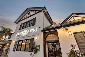 Un edificio de dos pisos con un letrero que dice 'PALM AND PAWN' y una señal verde que indica un lugar cercano.