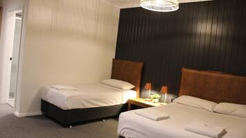 A hotel room with two beds, a dark wooden headboard, a white ceiling, and a hanging light fixture.