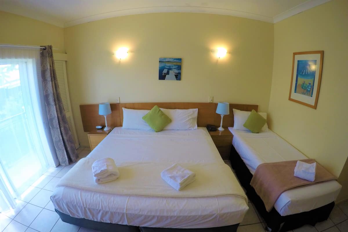A hotel room with two beds, a large window with curtains, and two bedside lamps.