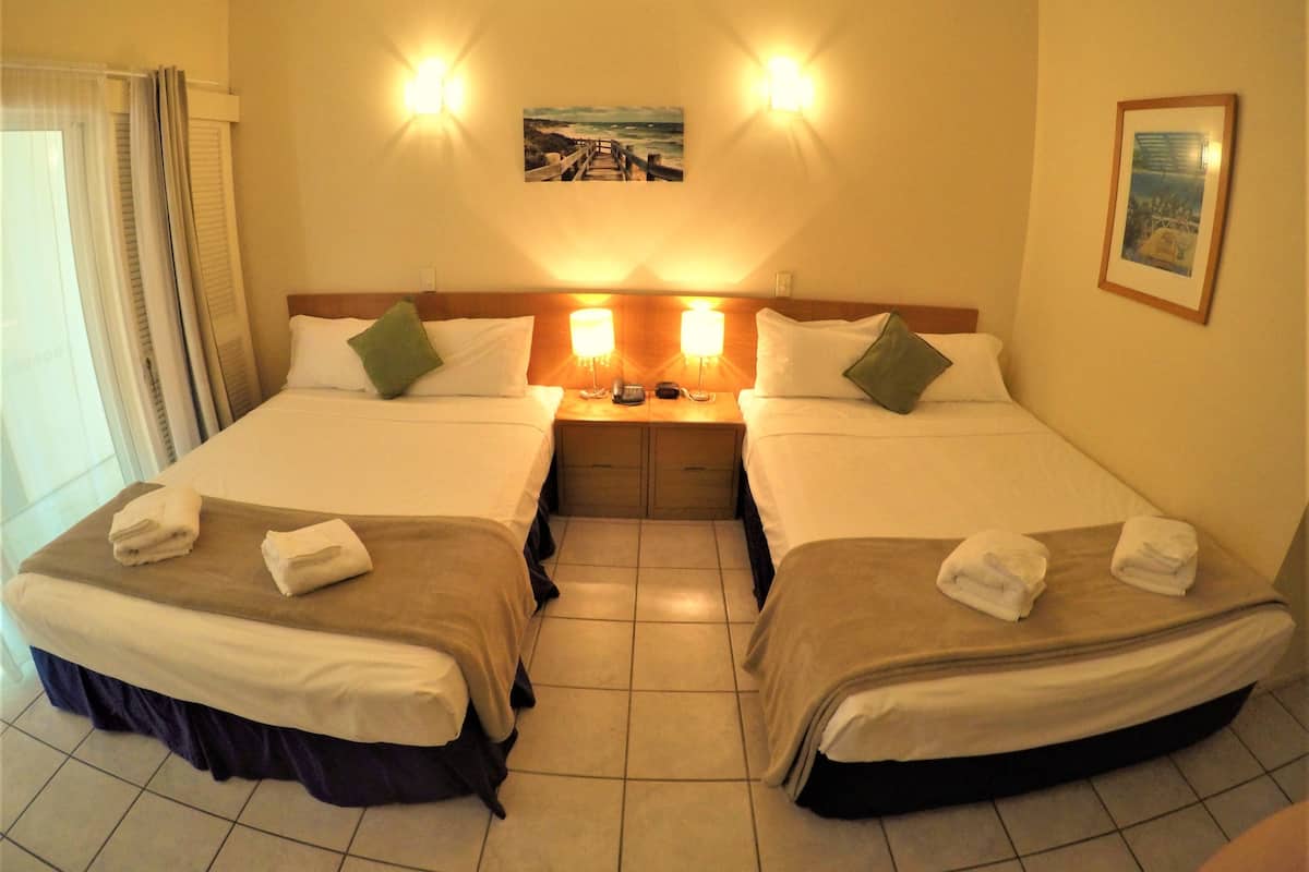 A hotel room with two beds, a nightstand with a lamp, and a painting on the wall.