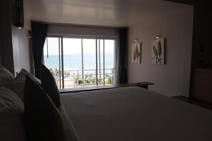 A bedroom with a large bed, a view of the sea, and two wall-mounted plant paintings. - Bari Lamai Resort (Rayong)