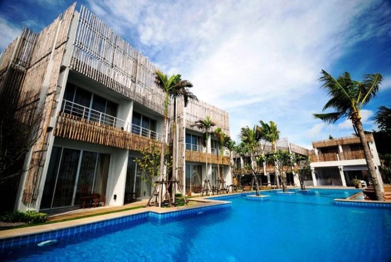A hotel with a pool area, multiple buildings, and palm trees.