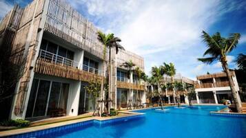 A hotel with a pool area, multiple buildings, and palm trees.