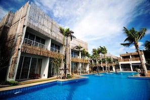 A hotel with a pool area, multiple buildings, and palm trees. - Bari Lamai Resort (Rayong)