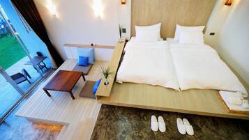 A modern bedroom with a large bed, a small table, and a view of the outdoors.