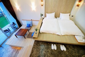 A modern bedroom with a large bed, a small table, and a view of the outdoors. - Bari Lamai Resort (Rayong)