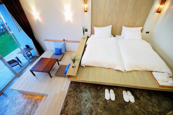 A modern bedroom with a large bed, a small table, and a view of the outdoors. - Bari Lamai Resort (Rayong)