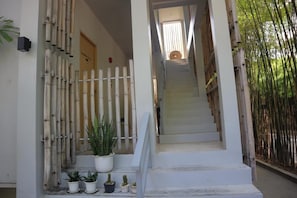 A staircase leading to a room with a bamboo fence on the left and a potted plant at the bottom. - Bari Lamai Resort (Rayong)