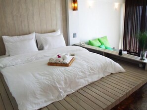 Habitación de hotel con una cama grande, una plataforma de madera y vistas al mar.