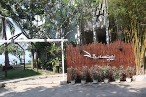 A resort entrance with a bamboo fence, potted plants, and a pergola. - Bari Lamai Resort (Rayong)