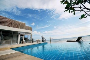 A modern poolside area with a clear view of the ocean, a pool, and a building with a sloped roof. - Bari Lamai Resort (Rayong)
