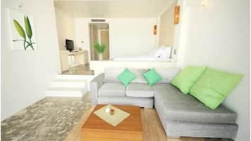 A modern living room with a grey sofa, green cushions, a wooden coffee table, and a staircase leading to an upper level.