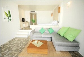 A modern living room with a grey sofa, green cushions, a wooden coffee table, and a staircase leading to an upper level. - Bari Lamai Resort (Rayong)