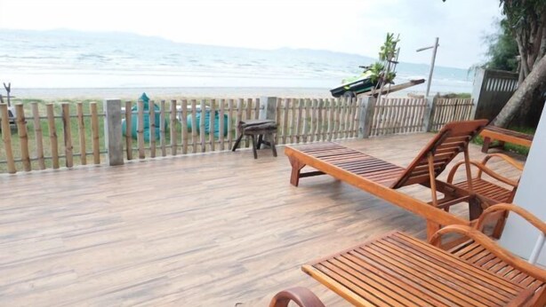 A wooden deck with a view of the ocean, a wooden table, and two wooden chairs. - Bari Lamai Resort (Rayong)