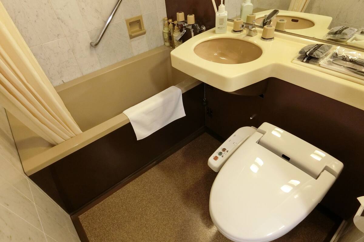 A bathroom with a white toilet, beige sink, and a towel hanging on a rack.