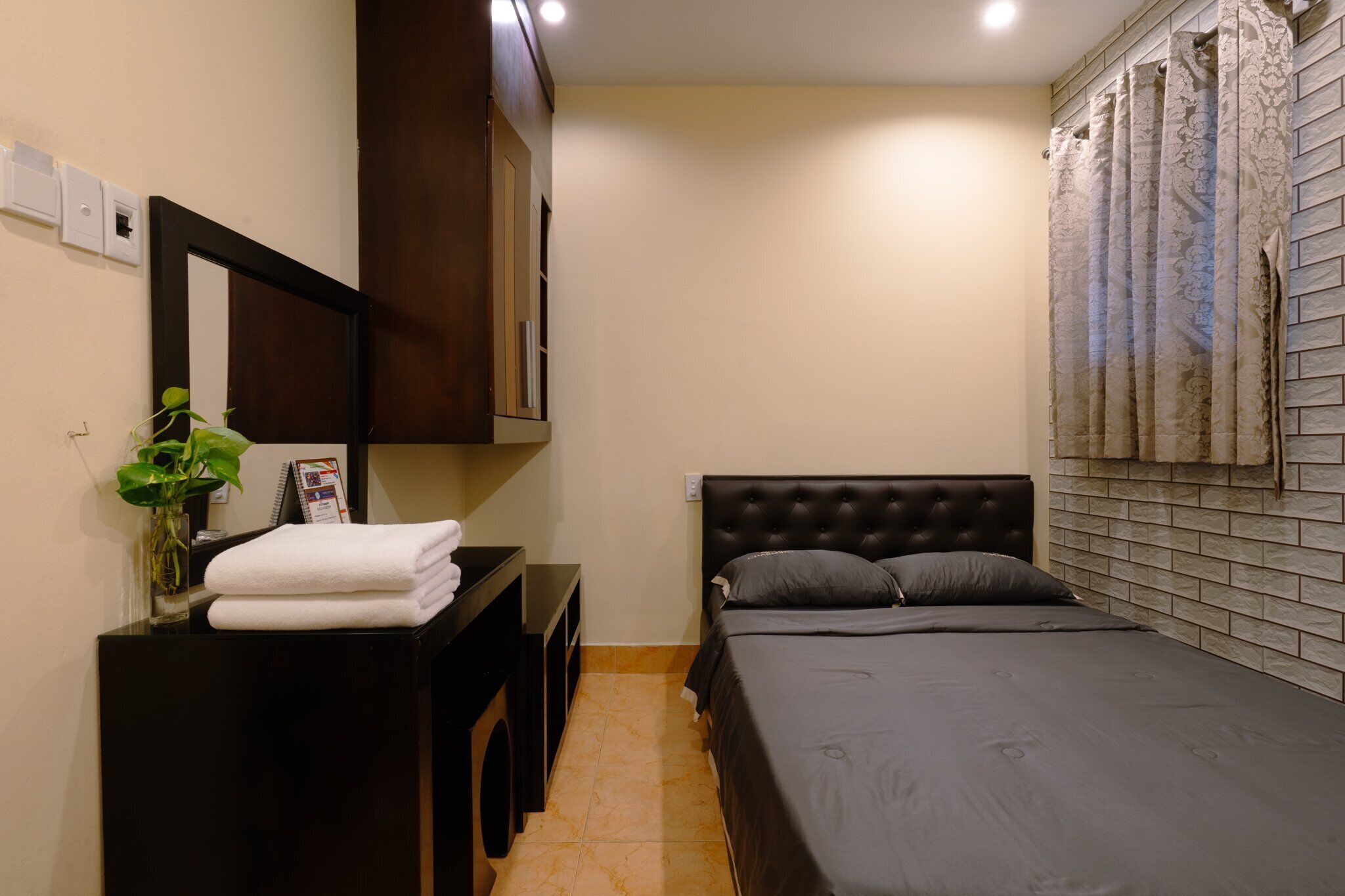 A bedroom with a bed, a nightstand, a mirror, and a wall-mounted TV.