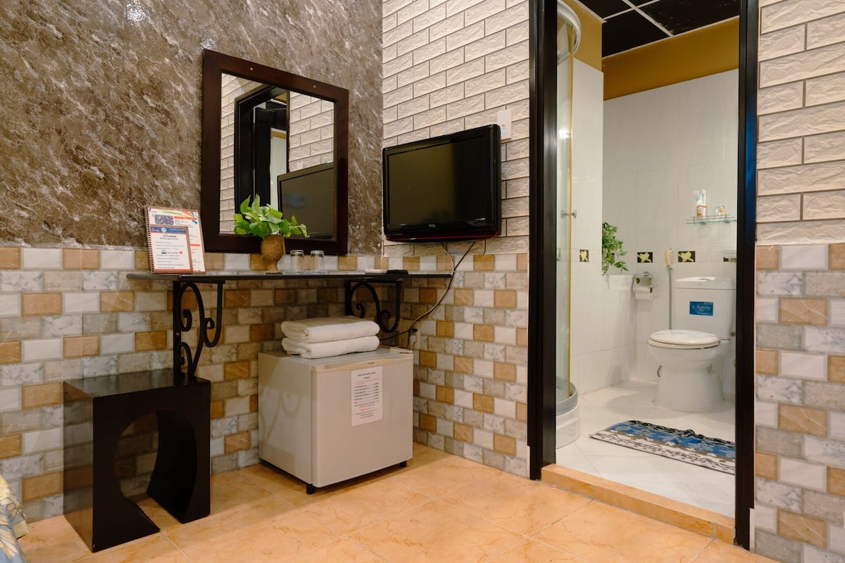 Un baño con pared de azulejos, lavamanos, inodoro y zona de ducha.