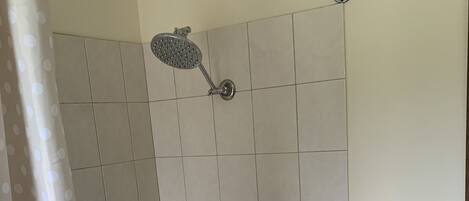 A shower area with a handheld showerhead, a handheld showerhead, a handheld showerhead, a handheld showerhead, and a handheld showerhead.
