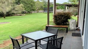 A patio with a table and chairs, a covered area, and a lawn.